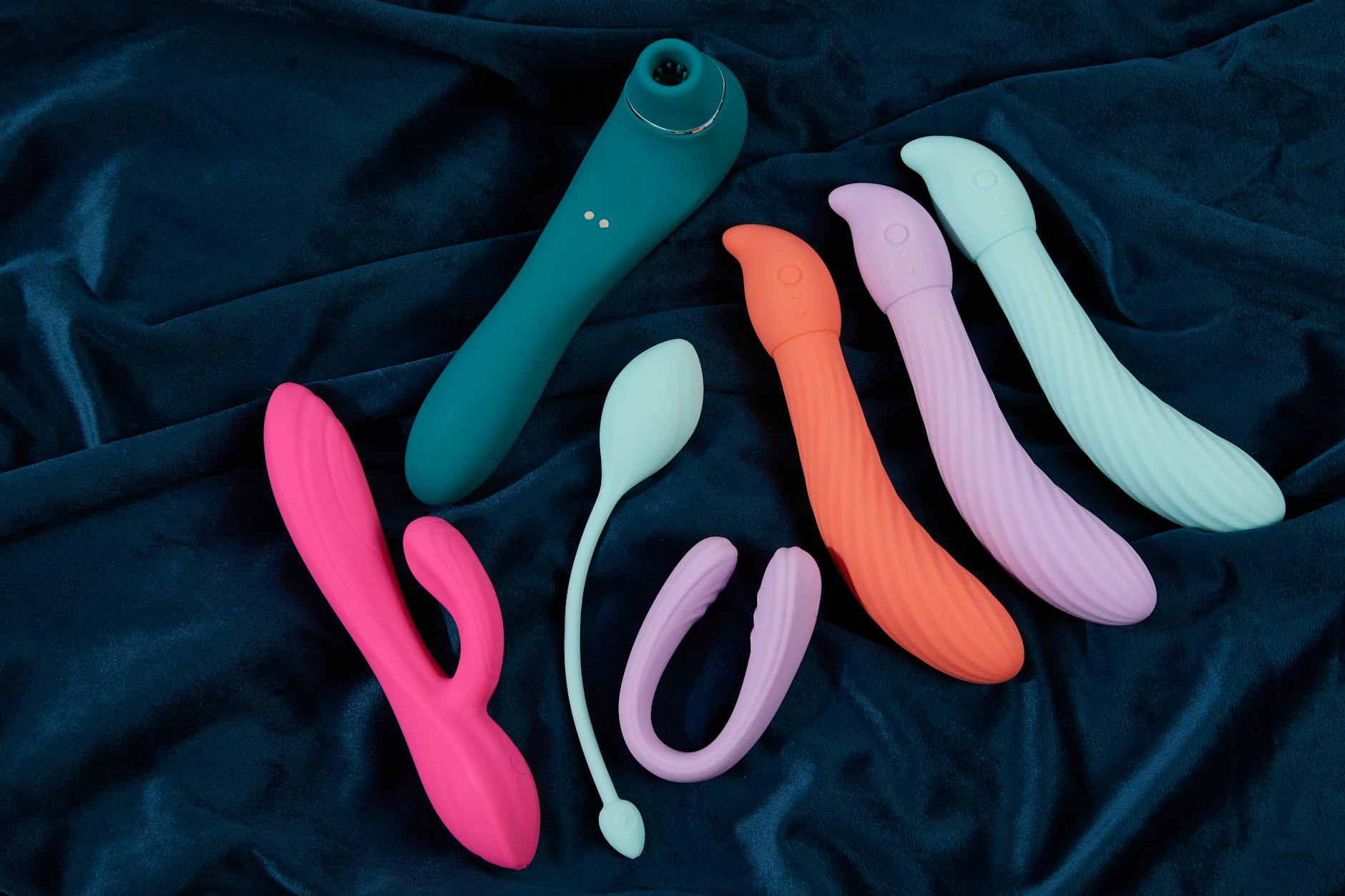 Woman holding contemplatively a blue and pink clitoral vibrator