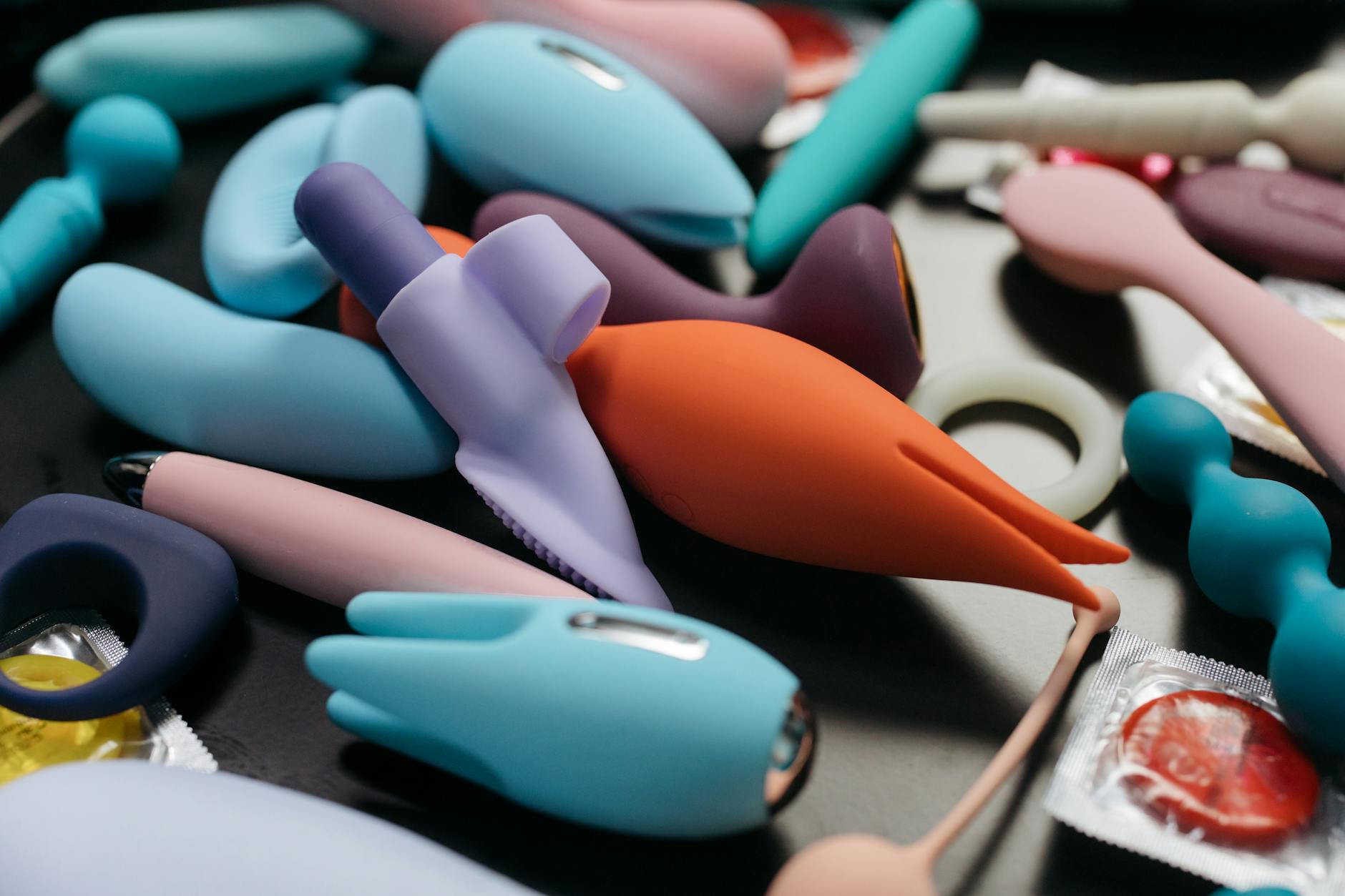 Un ensemble vibrant de vibromasseurs colorés incluant des vibromasseurs et des bagues sur un arrière-plan mettant en avant les jouets pour adultes modernes.