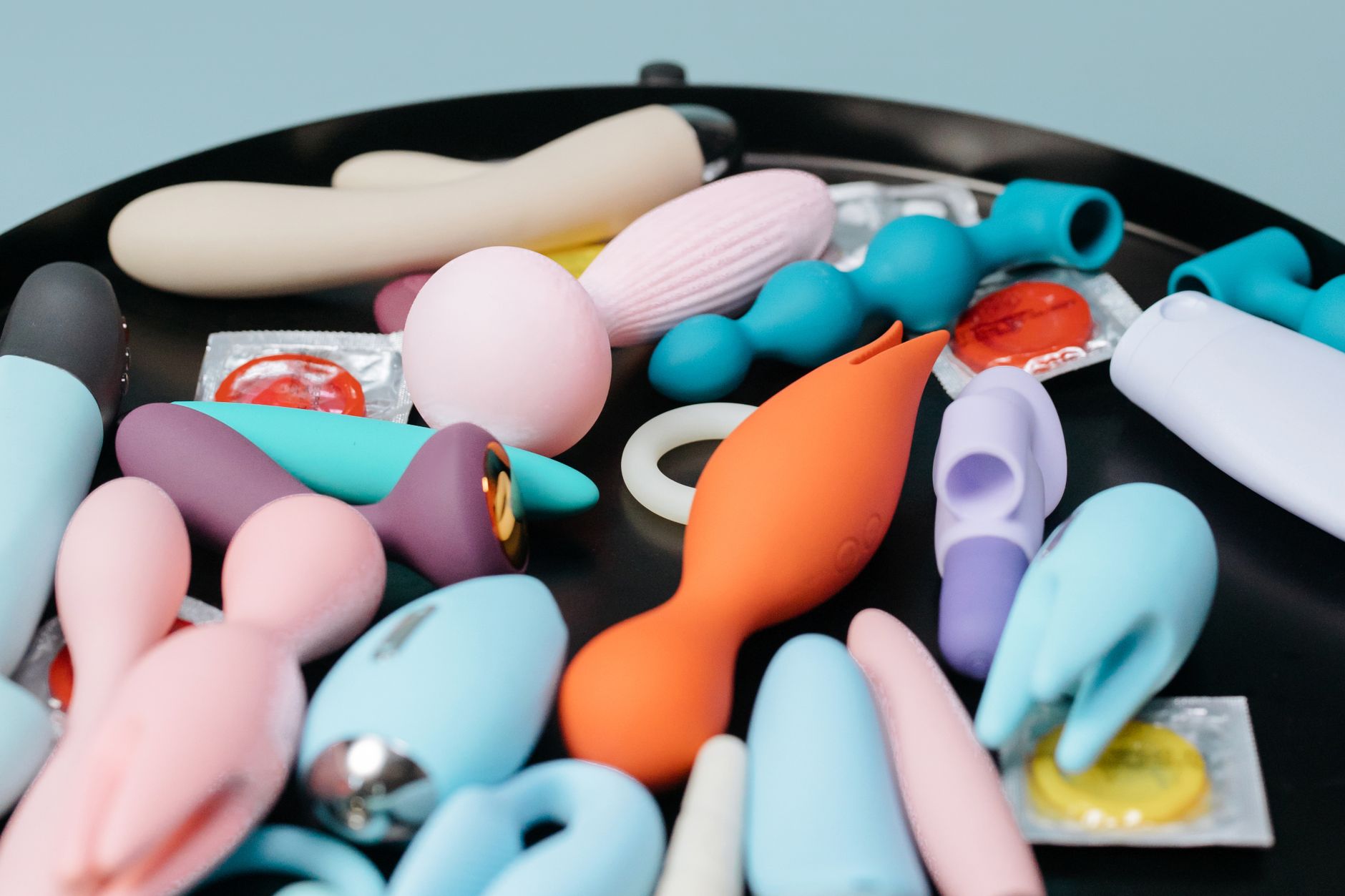 Collection de vibromasseurs colorés sur un plateau noir, montrant différentes formes et couleurs de toys érotiques