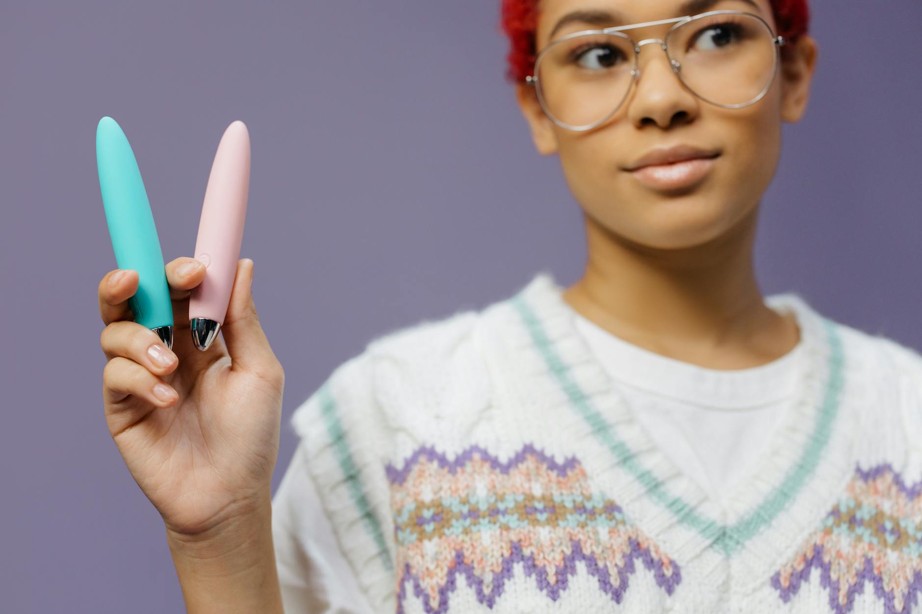 Deux mains tenant des jouets érotiques en silicone rose et bleu, symbole de complicité et d'exploration partagée.