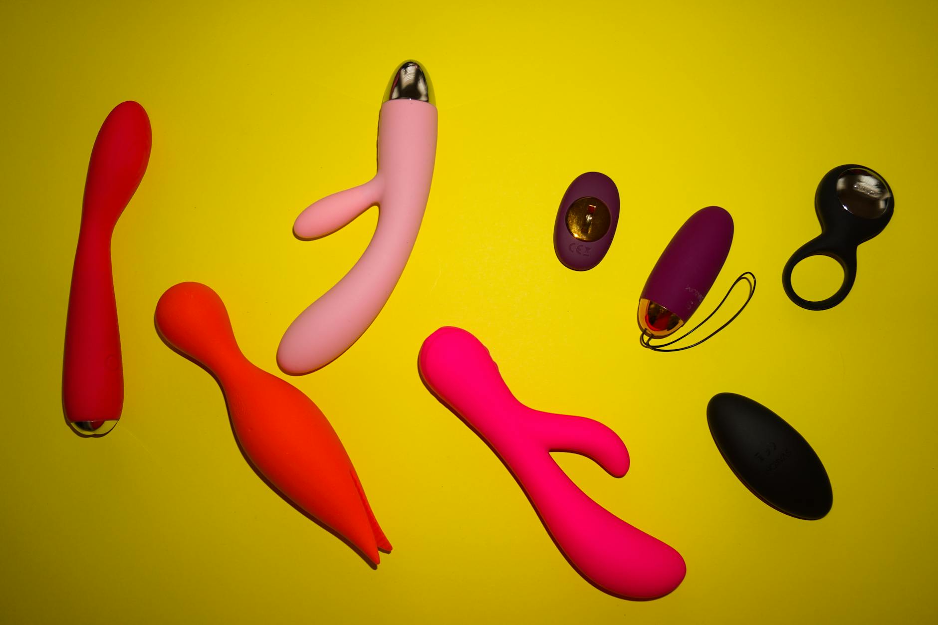 Colorful lemon vibrators and adult toys arranged on a bright yellow surface, showcasing design variety