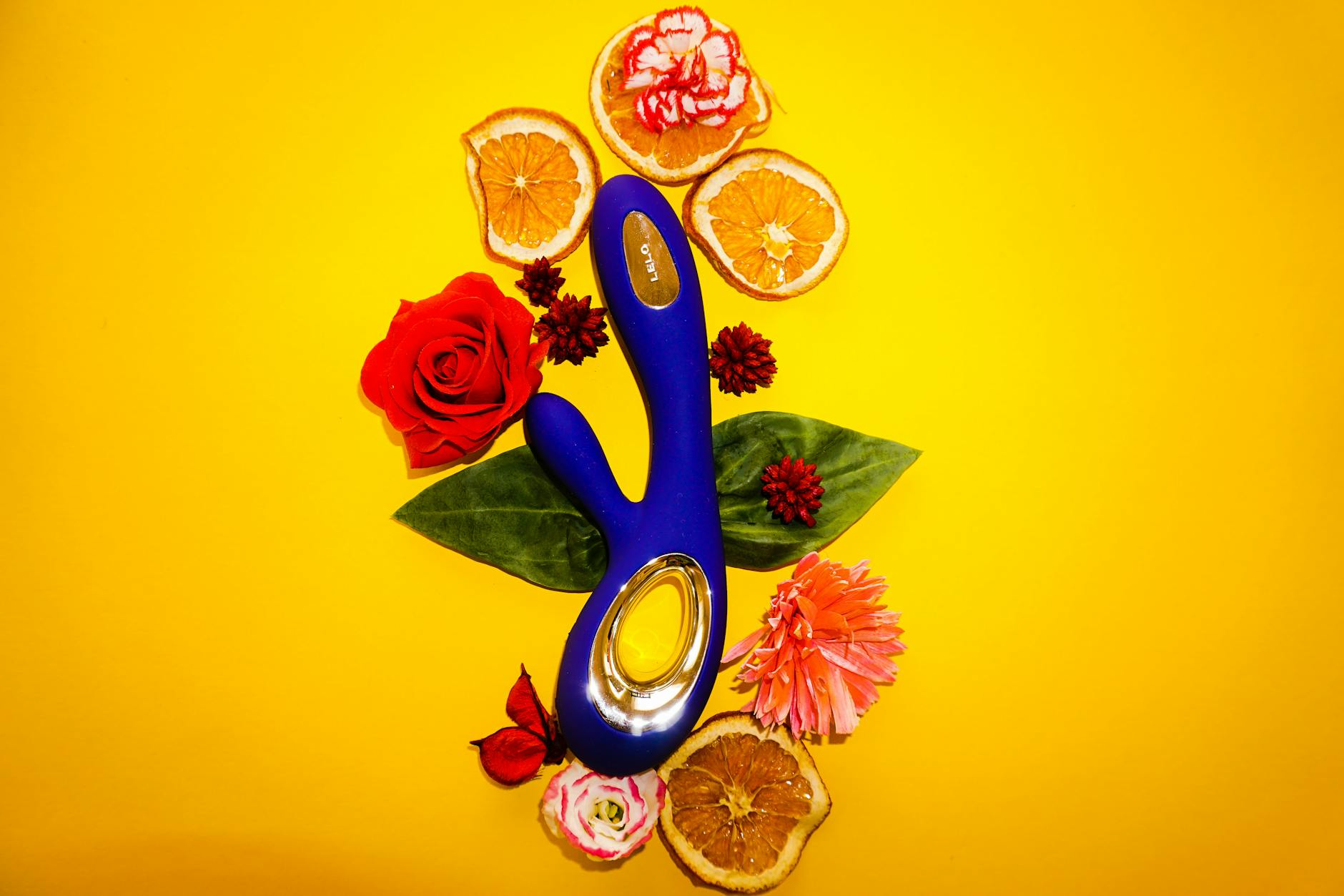 Lemon vibrator surrounded by fresh lemons and flowers on a bright yellow background